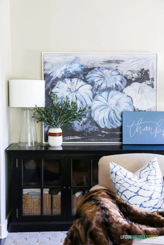 Gorgeous fall living room with navy blue and neutrals with olive leaf accents. Loving the mix of velvet and faux fur. Also love the large blue pumpkins canvas art and 'thankful' canvas.