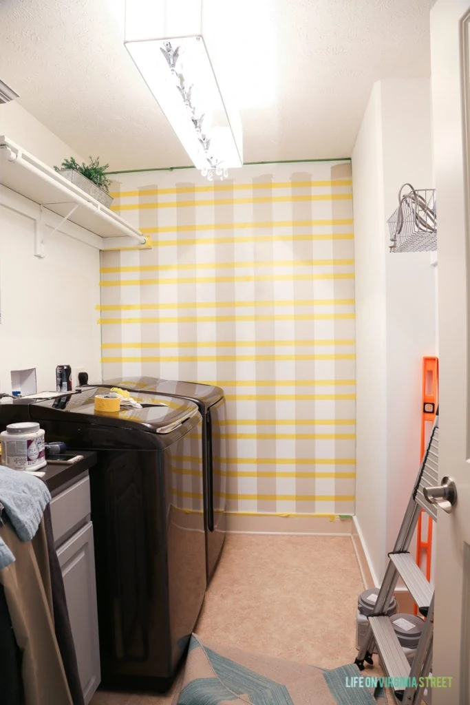 Yellow tape on wall horizontal from the beige painted lines on wall.