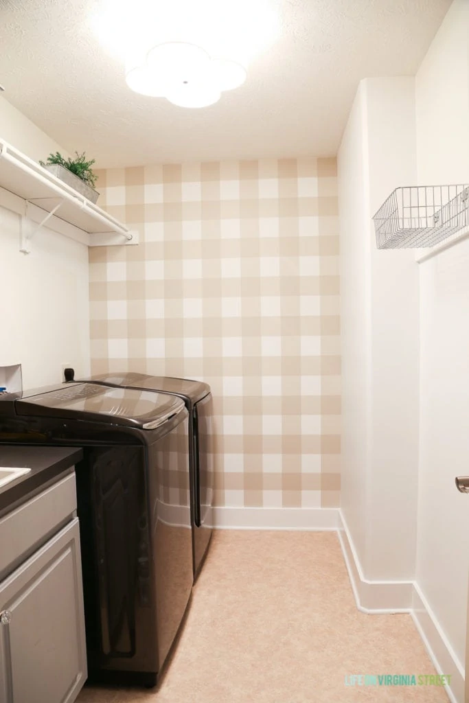 Buffalo checkered wall, painted baseboards and bright lighting fixture in updated laundry room.