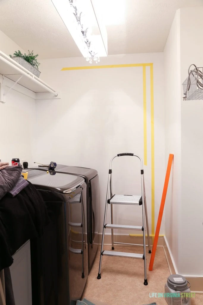 Yellow tape on wall for taping buffalo checks, plus a step ladder in laundry room.