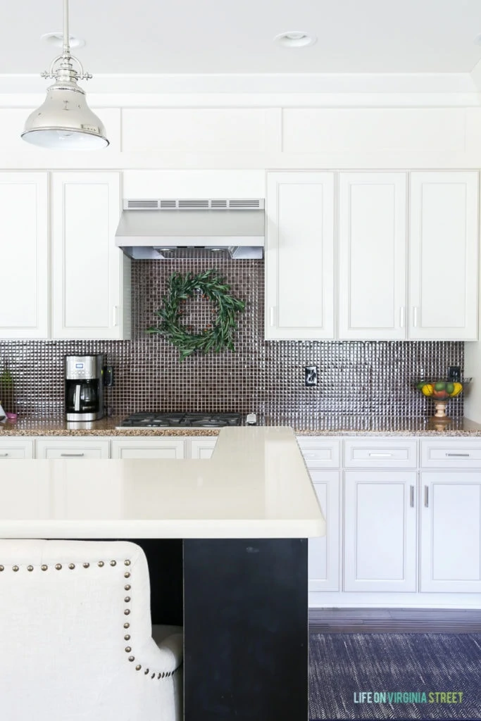 White kitchen with olive wreath over range and a pendant light over the kitchen island.