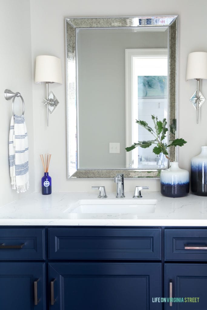 Powder bathroom with Behr Castle Path walls, Benjamin Moore Hale Navy vanity, chrome star sconces, chrome faucet, and ombre blue vases.