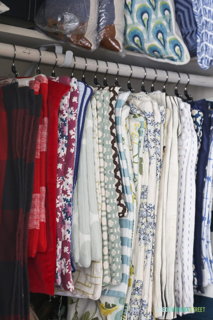 Fabric hanging in closet with pillows on shelf above.