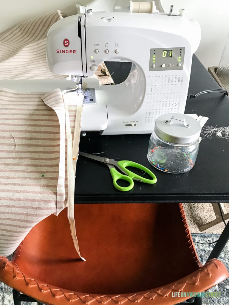Sewing machine on counter with scissors and pins.
