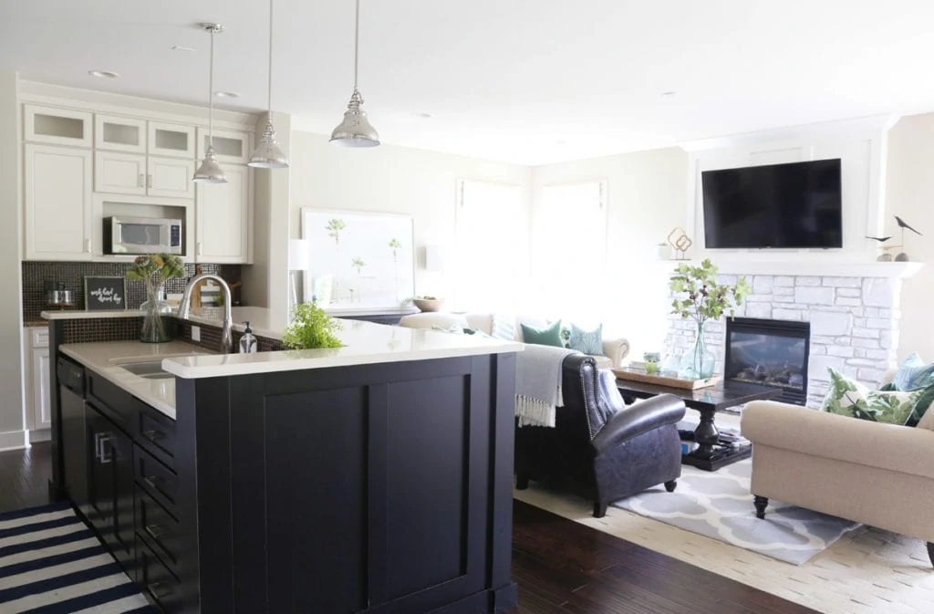 A kitchen island plus living room chairs and dark floors.