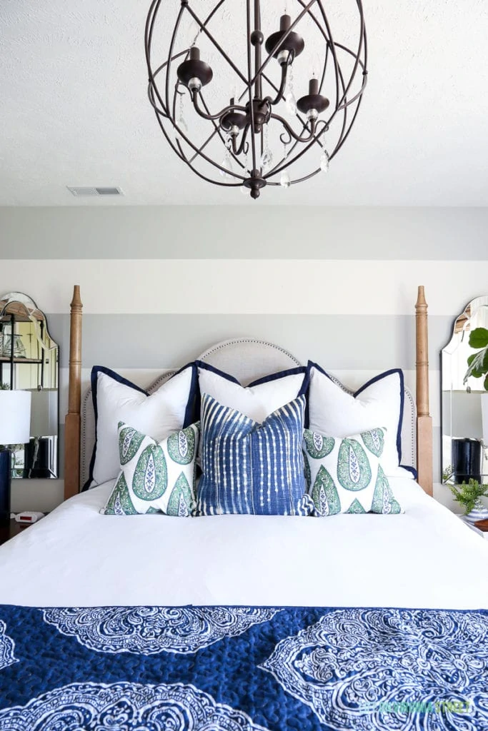 Blue an white bedding with a chandelier over the bed.