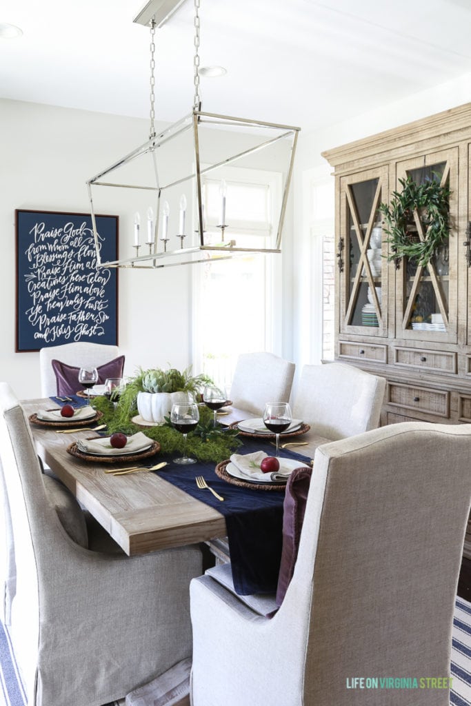 Dining table, with a navy blue runner, and candle chandelier above table.