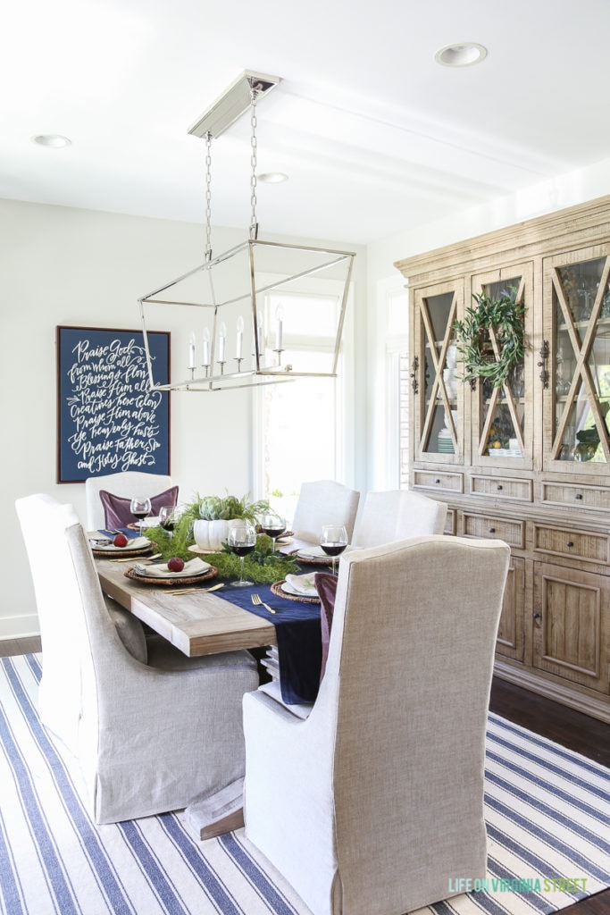 Dining room table with upholstered chairs around it and a blue and white striped rug.