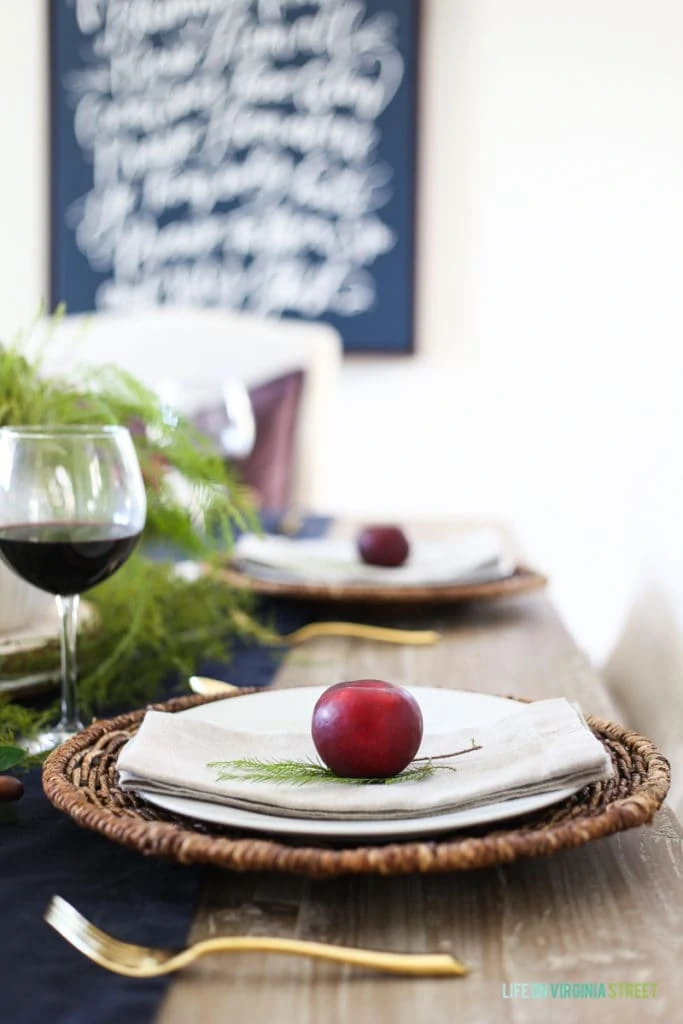 The purple plums on the plate on the table and a glass of red wine. 