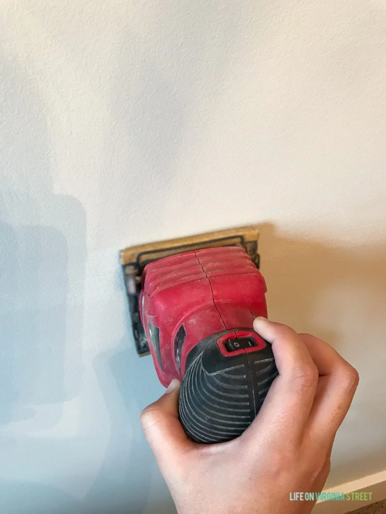 The electric sander, sanding the striped wall.