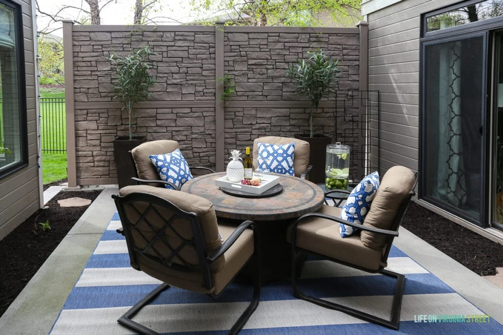 The same side patio with a blue and white rug, a round table and chairs with blue and white pillows.