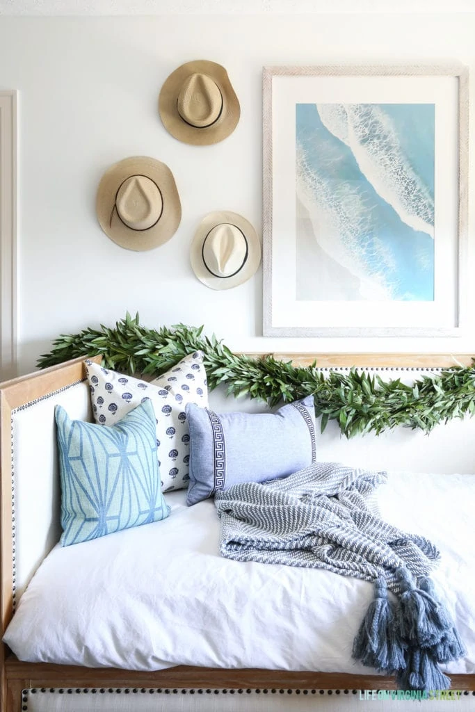 Christmas touches over a beachy daybed. I love the woven hats on the walls paired with the beachy artwork.