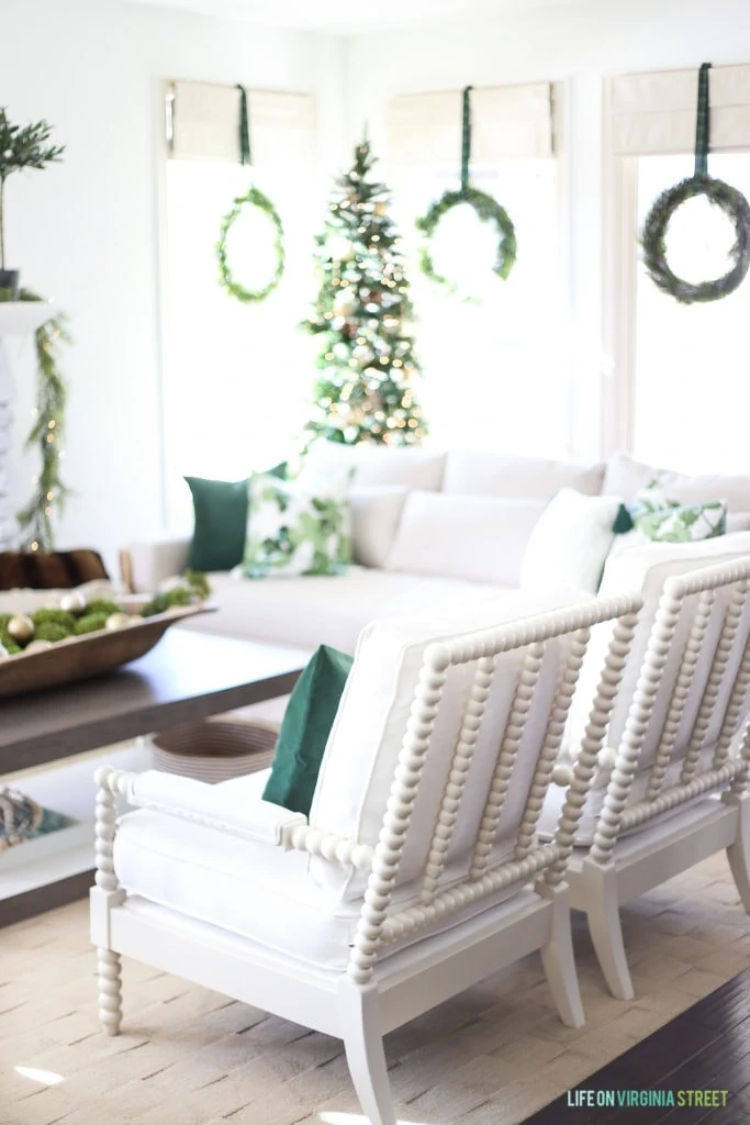 White spindle chairs with dark green velvet pillows.