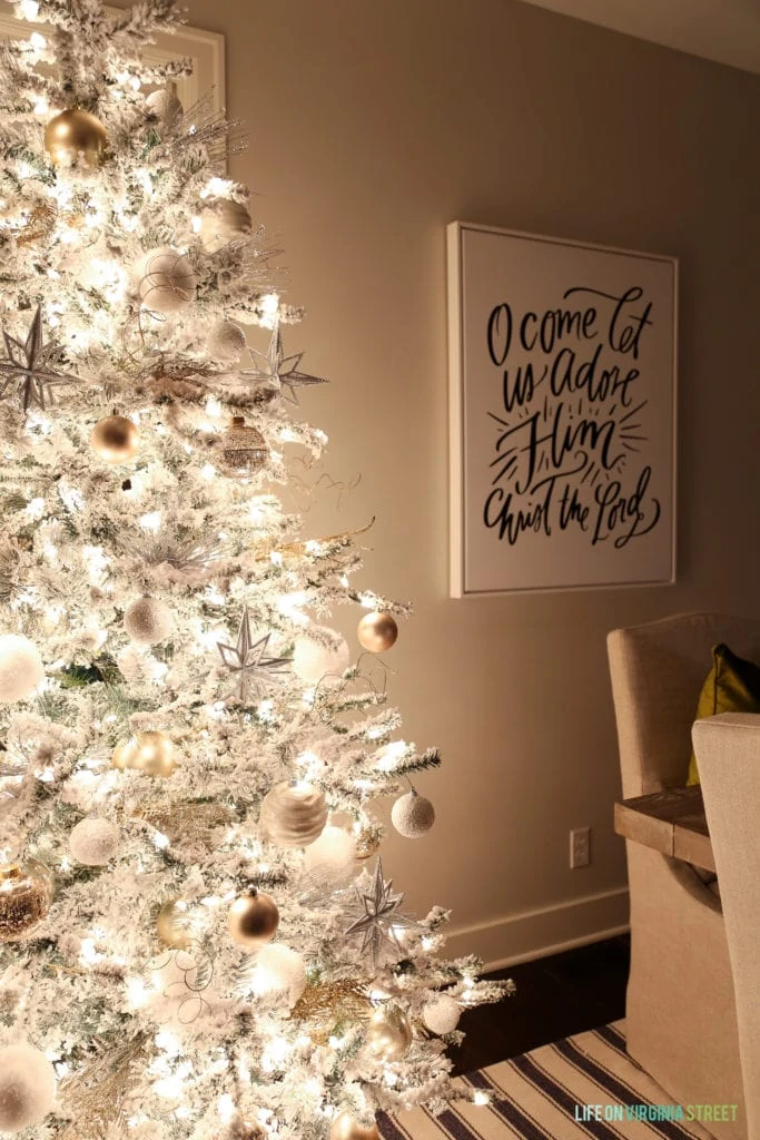White flocked Christmas tree with white and gold ornaments on it.