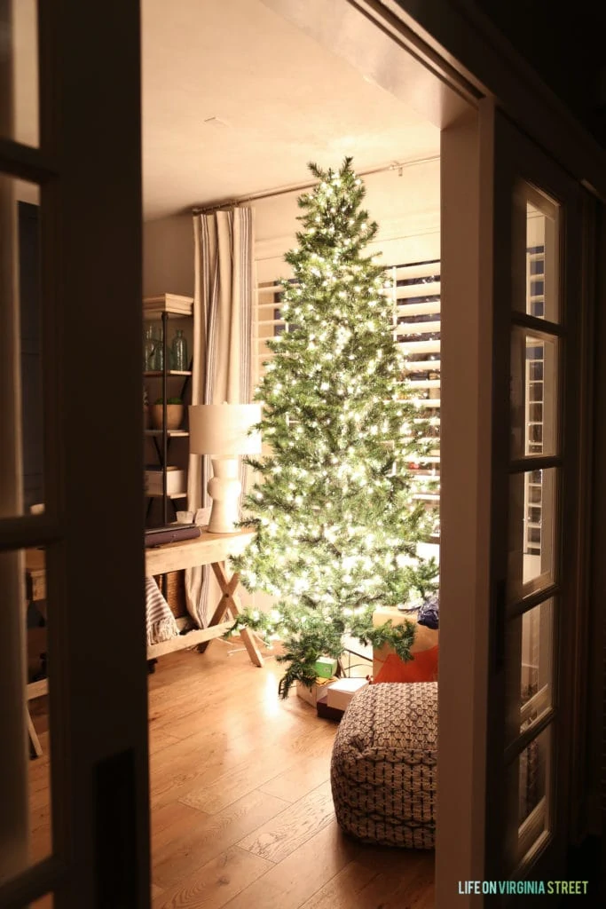 Large Christmas tree in office with white lights on it.