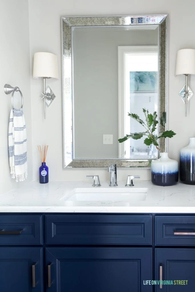 A bathroom cabinet painted blue with a white countertop and a small blue an white vase.