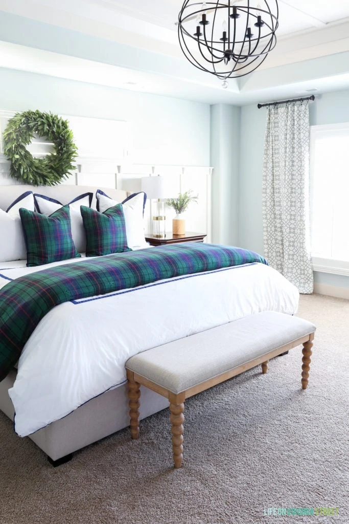 Bedroom with Sherwin Williams Sea Salt walls, white duvet cover, plaid comforter, orb chandelier and bayleaf wreath over bed.