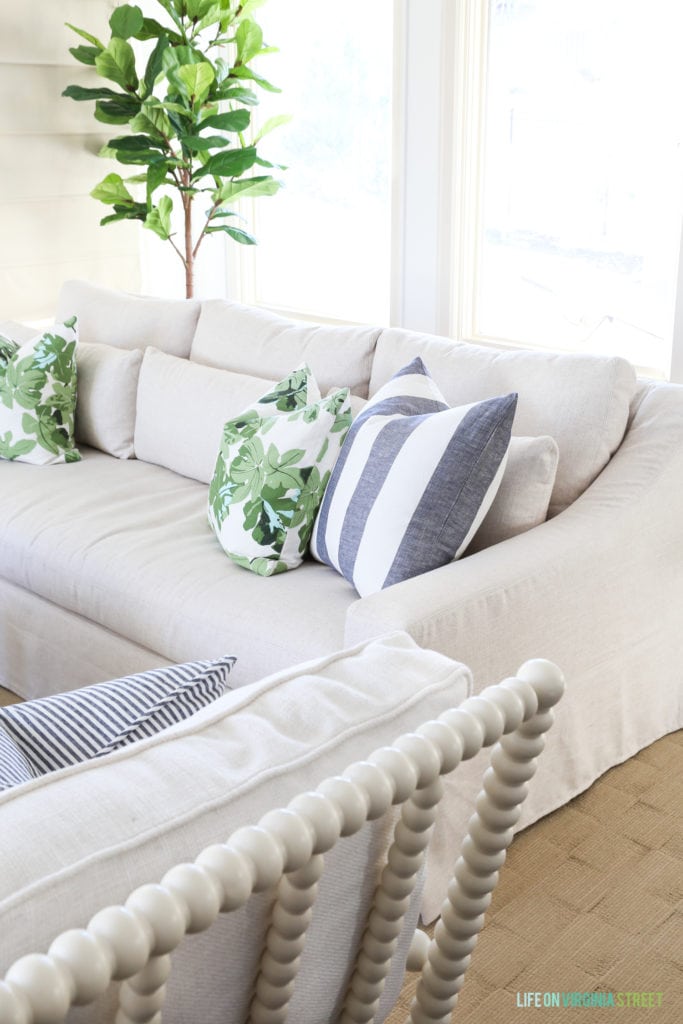 A striped blue and white pillow, plus a green and white pillow both on the couch.