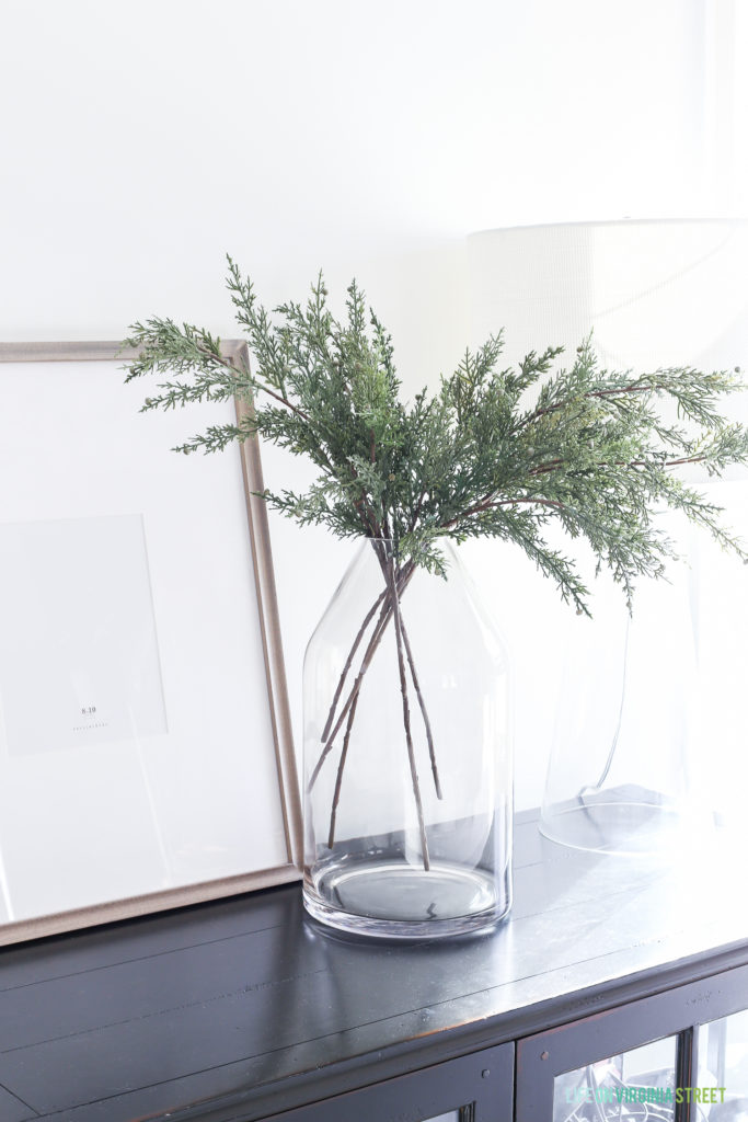 Evergreen branches in a clear vase on the console table.