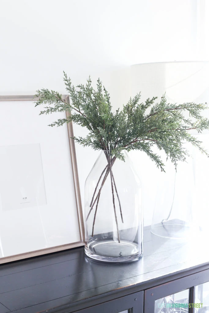 Evergreen branches in a clear vase on the console table.