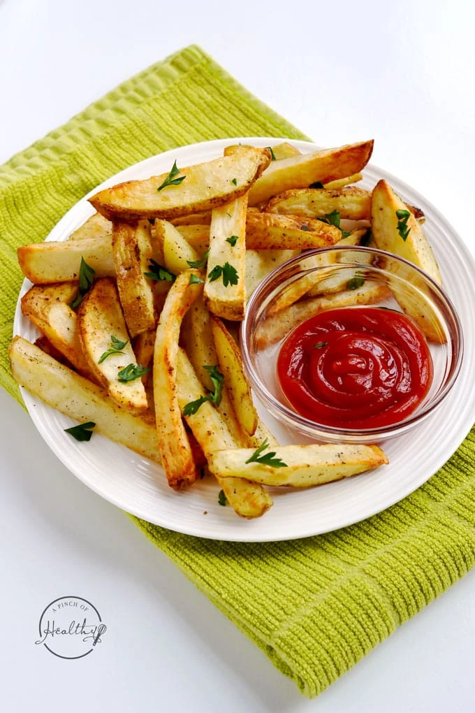 Air fried French fries with a bowl of ketchup beside it.