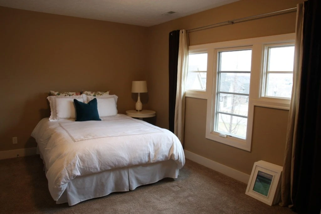 A guest bedroom with dark walls, a small bed with white bedding.