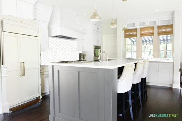 A white and grey island in the kitchen with a white backsplash.