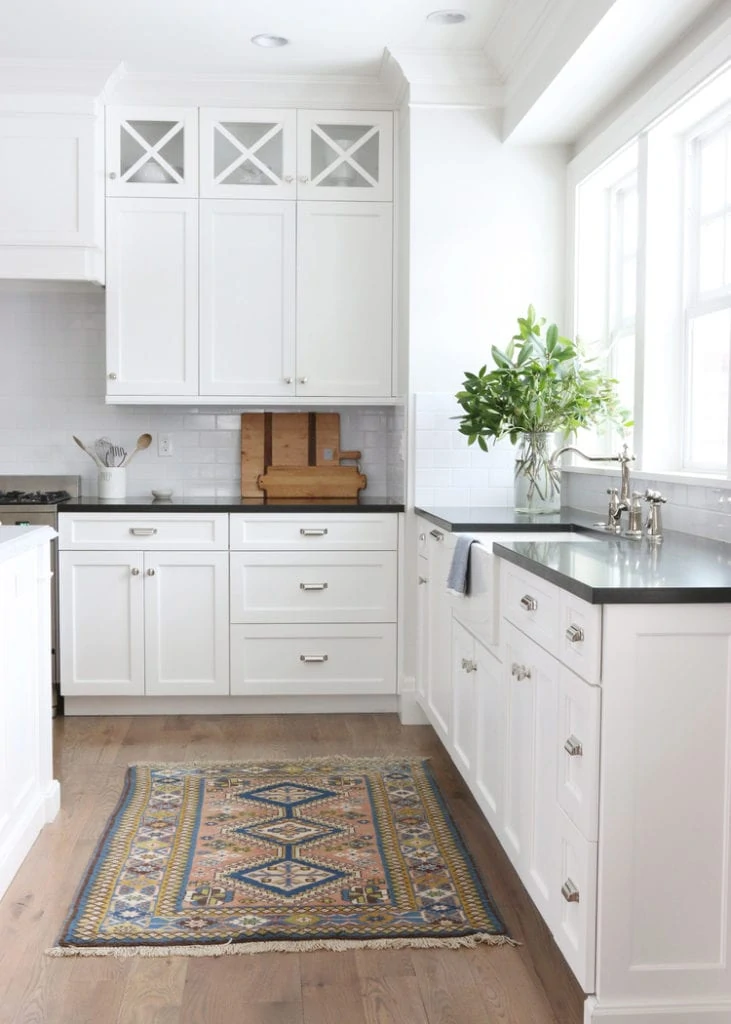 White cabinets in the kitchen with a vase of greenery on the counter.