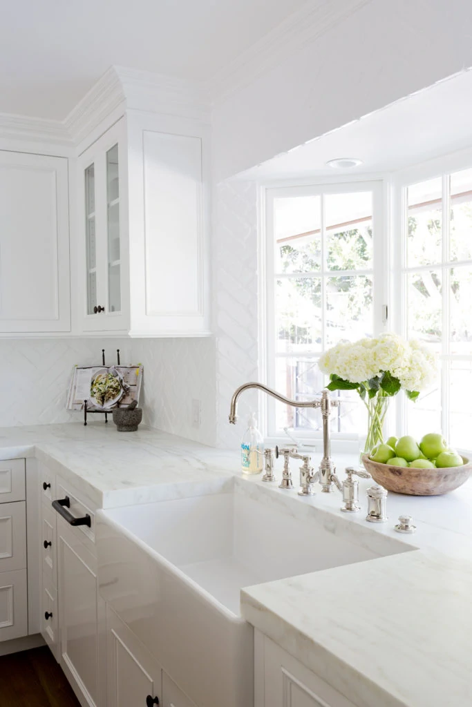 A white backsplash in a white kitchen with a large farmhouse sink.