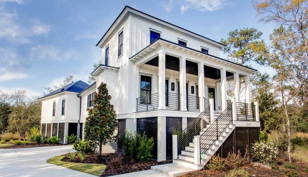 A modern farmhouse painted Benjamin Moore Chantilly Lace. Windows are black frames with gray trim.