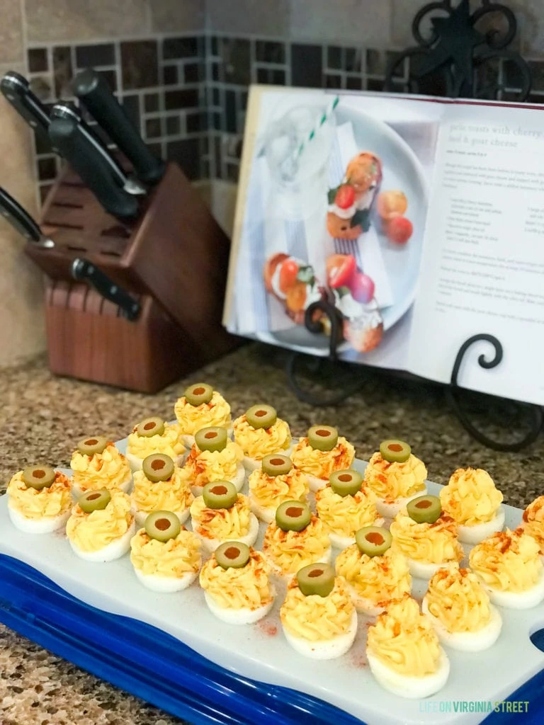 A cookbook on a stand behind the deviled eggs on a platter.