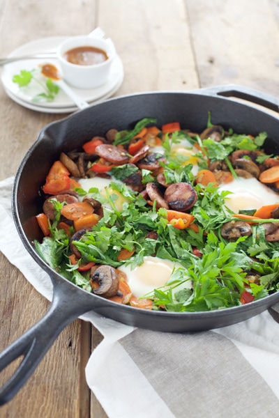 Eggs, tomatoes, potatoes and fresh greens in a skillet.