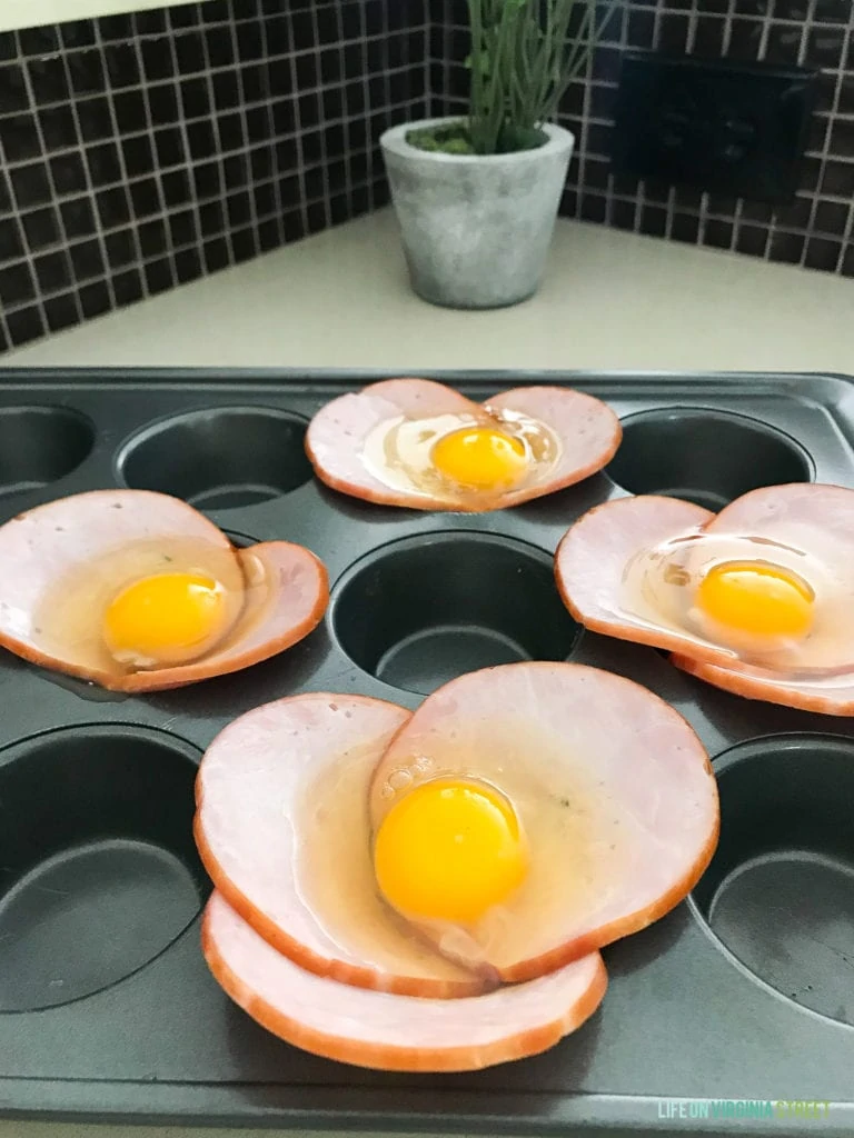 A cracked egg over the bacon in the muffin tin.