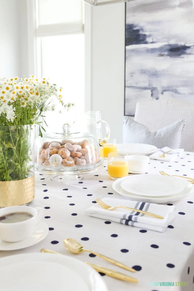 A covered cake stand filled with donuts and daisy flowers in the centre of the table.