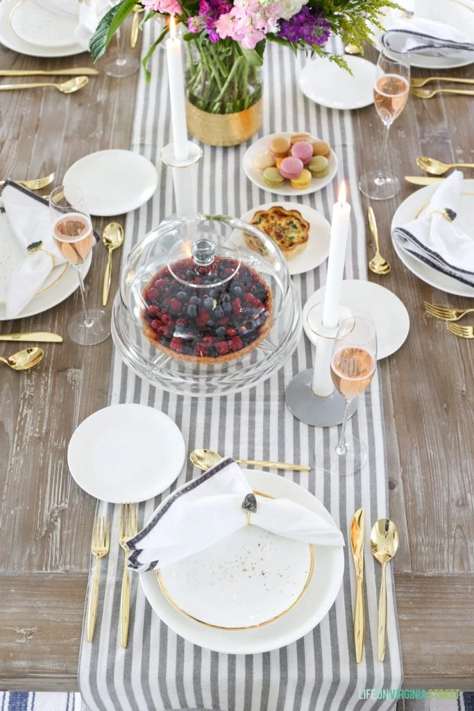 A berry pie, macarons and a set table in dining room.