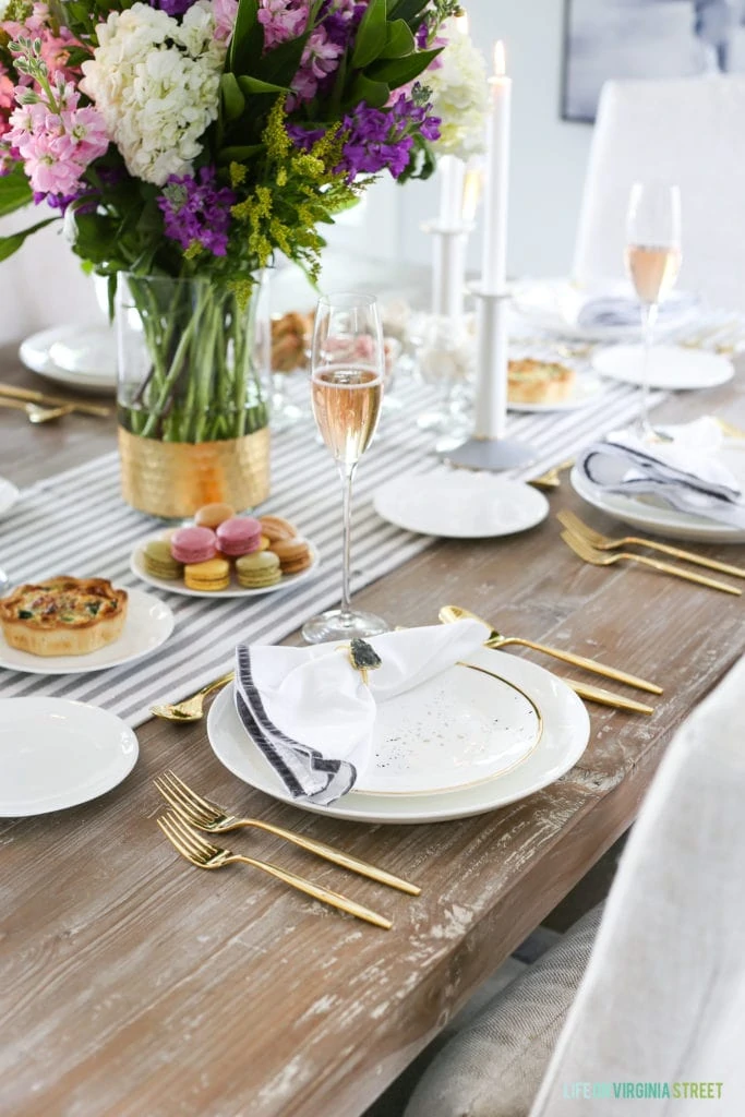 A glass of champagne and a floral arrangement on the dining room table.