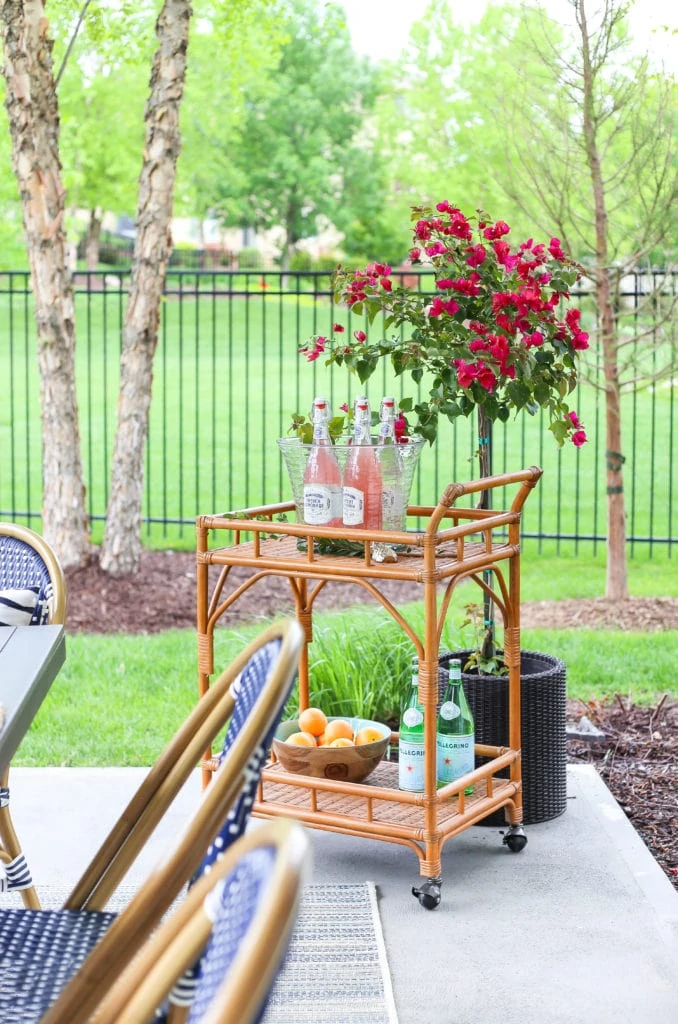 Outdoor rattan barcart with drink station and bougainvillea.