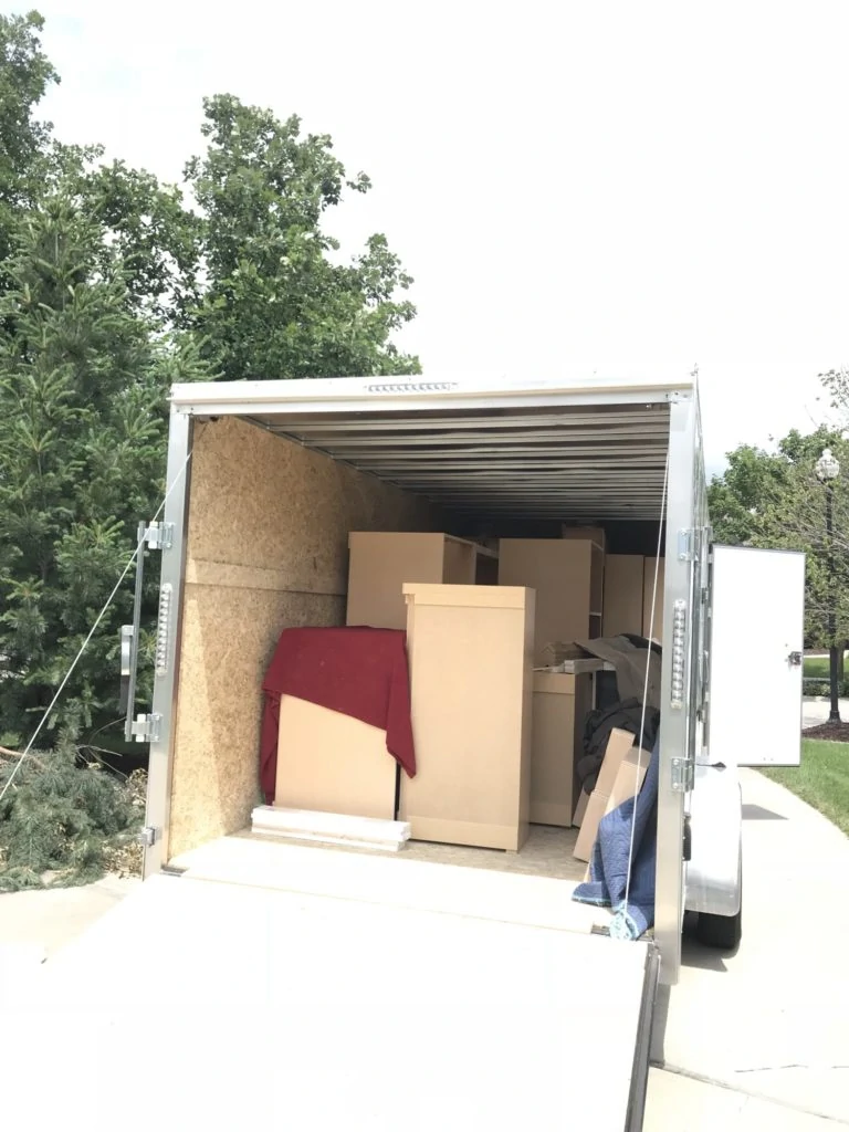 A delivery truck with the door opened in the back and boxes stacked up.