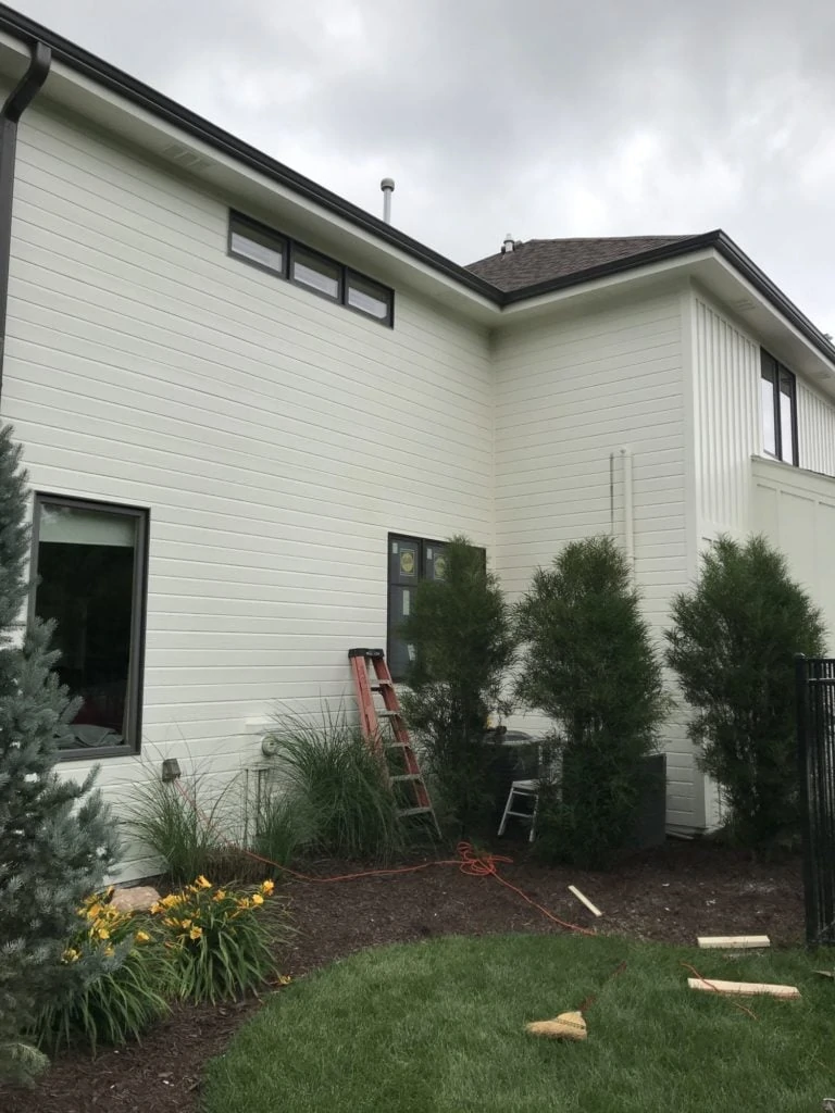 Working on the outside of the house with a ladder leaning against the house.