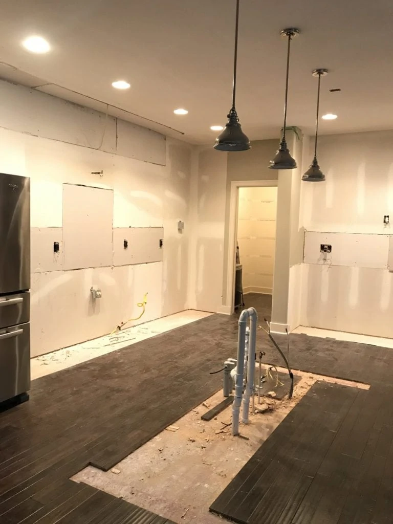 The empty kitchen with the plumbing showing.