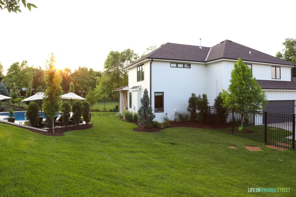 White painted house with a dark brown wrought iron fence and a pool.