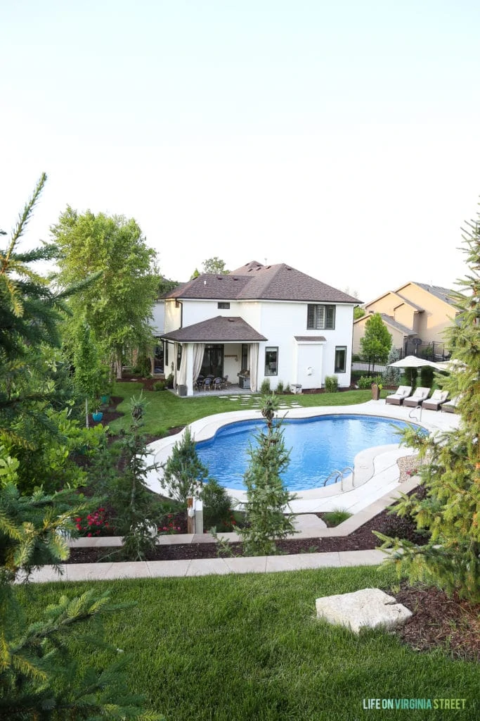 A far away photo of the house with the pool and grassy area.