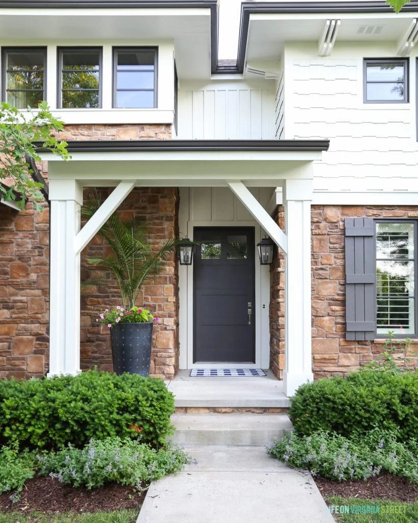 A white painted house with natural stone and dark brown trim and door.