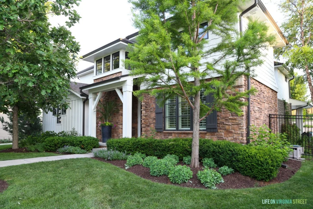 Side view of the house with landscaped front yard and shutters on the windows.