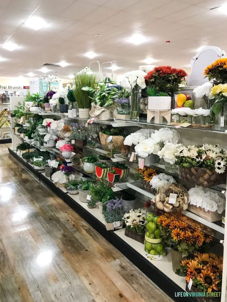 Many faux flowers and vases for sale on a store shelf.