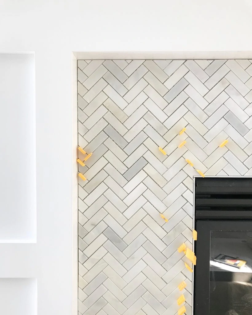 Carrara marble herringbone tile on a fireplace surround.