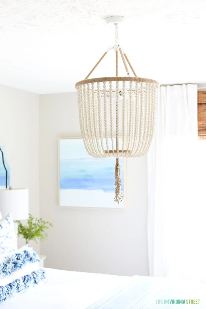 A beautiful white bead chandelier with jute trim and tassels. Love the vibe it adds to this beachy guest bedroom!