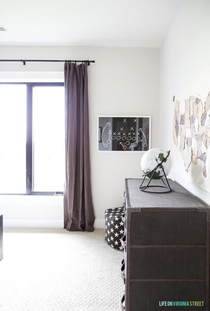 A dark wooden dresser and eggplant purple curtains in the boys room.
