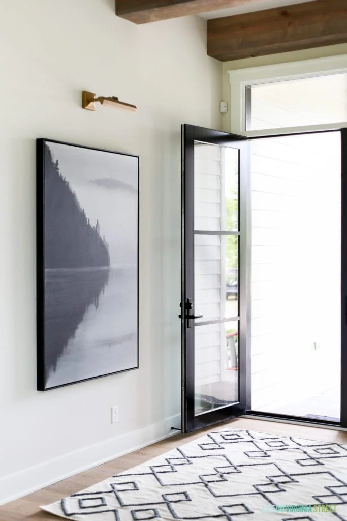 The entryway with a glass door which is open and a small area rug in white and black inside.