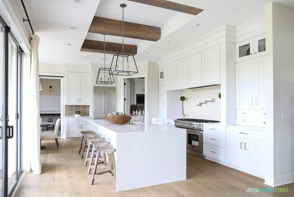 Large white kitchen with wood beams and a white island.